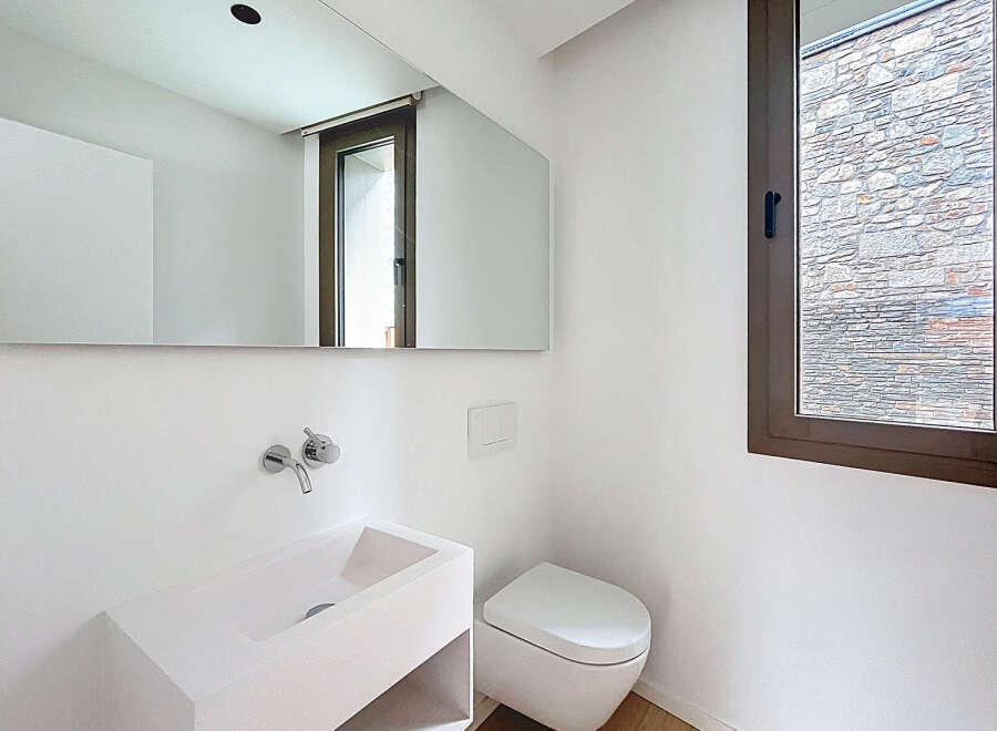 This modern bathroom features a sleek, minimalist design with a wall-mounted sink and toilet.
