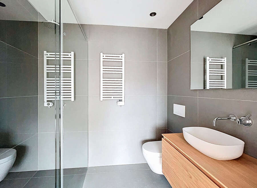 Step into a modern bathroom oasis! This stylish space features sleek gray tiles, creating a clean and contemporary aesthetic.