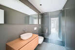 This modern bathroom features a sleek design with a glass shower enclosure and a floating wooden vanity.