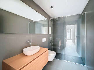 This modern bathroom features a sleek design with a glass shower enclosure and a floating wooden vanity.