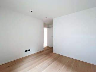 This bright and airy room features pristine white walls and elegant hardwood floors, creating a clean and modern aesthetic.