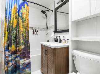 This stunning bathroom features a unique shower curtain with a vibrant nature scene, creating a serene and inviting atmosphere.