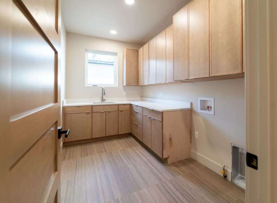 This stunning laundry room features custom cabinetry, offering ample storage space for all your needs.