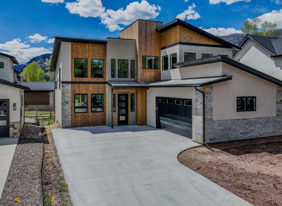 This stunning modern home boasts a striking exterior with a combination of wood and stone accents.