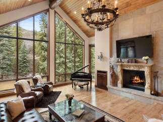 Experience luxury living in this stunning property featuring a grand piano, a cozy fireplace, and expansive windows that frame breathtaking views.