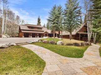 This stunning property boasts a beautiful wooden exterior and a grand driveway, perfect for luxurious living.