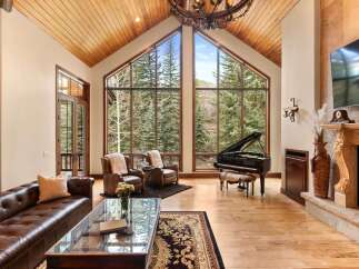 Experience luxury living in this stunning property, featuring a grand living room with soaring ceilings and expansive windows that frame breathtaking mountain views.