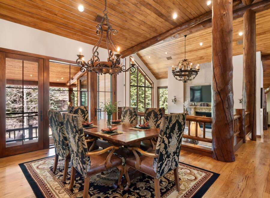 Step into luxury with this stunning dining room, featuring a rustic wooden ceiling and elegant chandeliers.