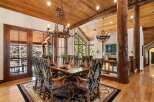 Step into luxury with this stunning dining room, featuring a rustic wooden ceiling and elegant chandeliers.