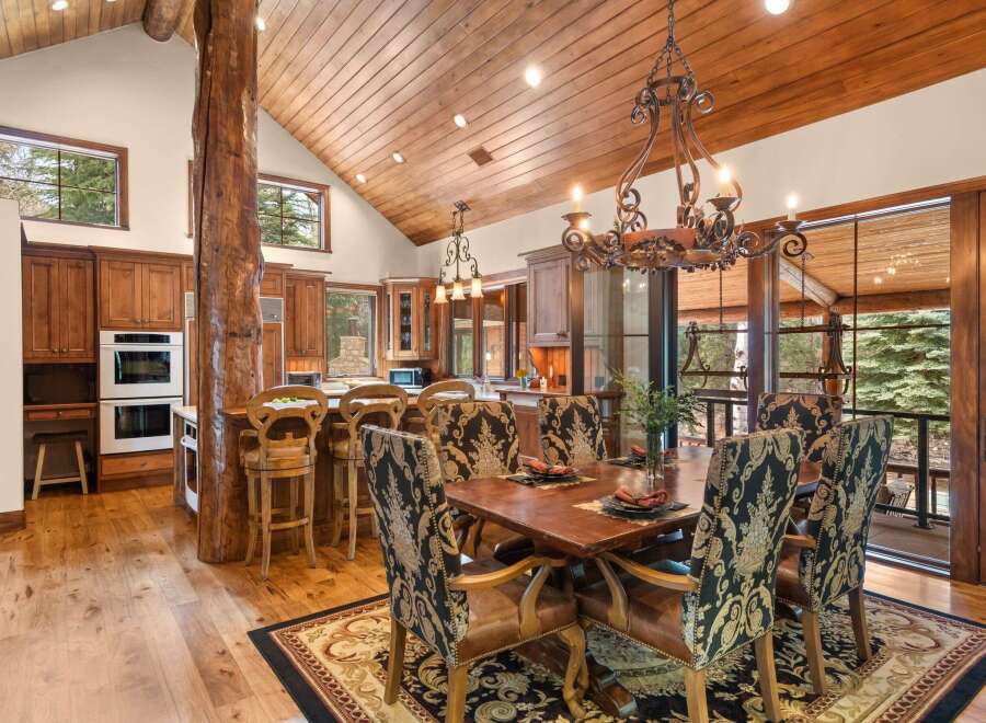 Step into luxury with this stunning dining room, featuring a rustic wooden ceiling and a grand chandelier.