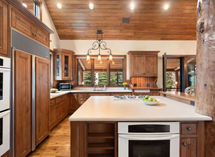 This stunning kitchen boasts custom wooden cabinetry, a spacious island with a cooktop, and a built-in oven.