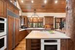 This stunning kitchen boasts custom wooden cabinetry, a spacious island with a cooktop, and a built-in oven.
