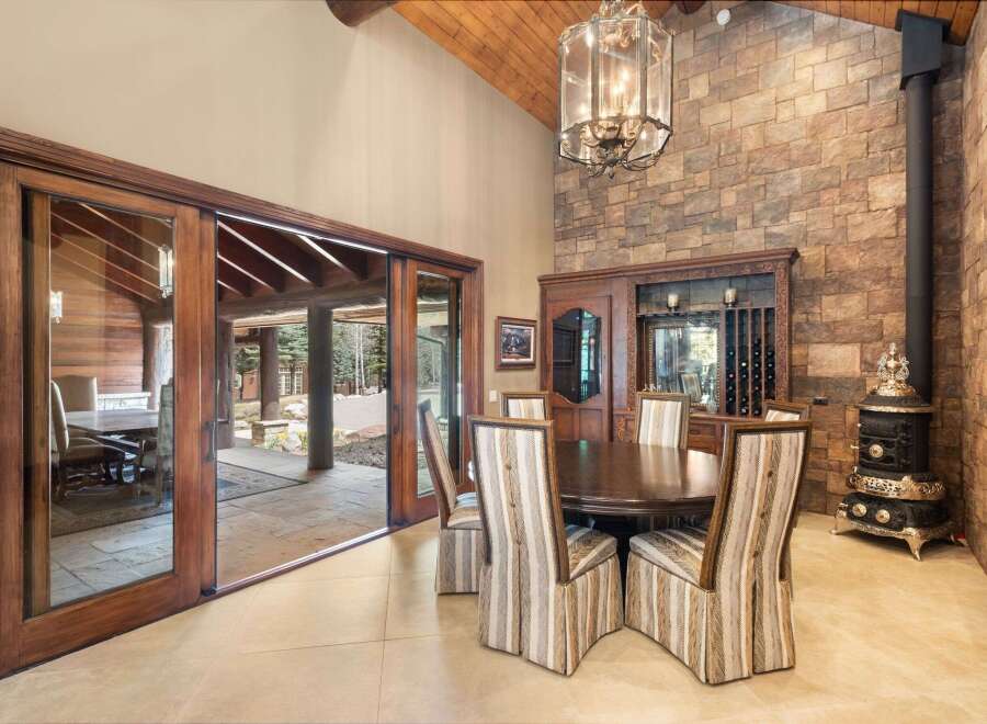 Step into luxury with this stunning dining room, featuring a beautiful stone accent wall and a grand chandelier.
