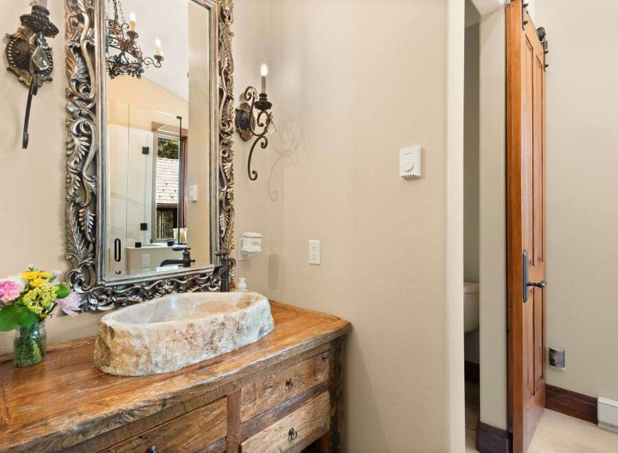 Step into luxury with this stunning bathroom! Featuring a unique stone sink and a beautifully crafted wooden vanity, this space exudes rustic elegance.