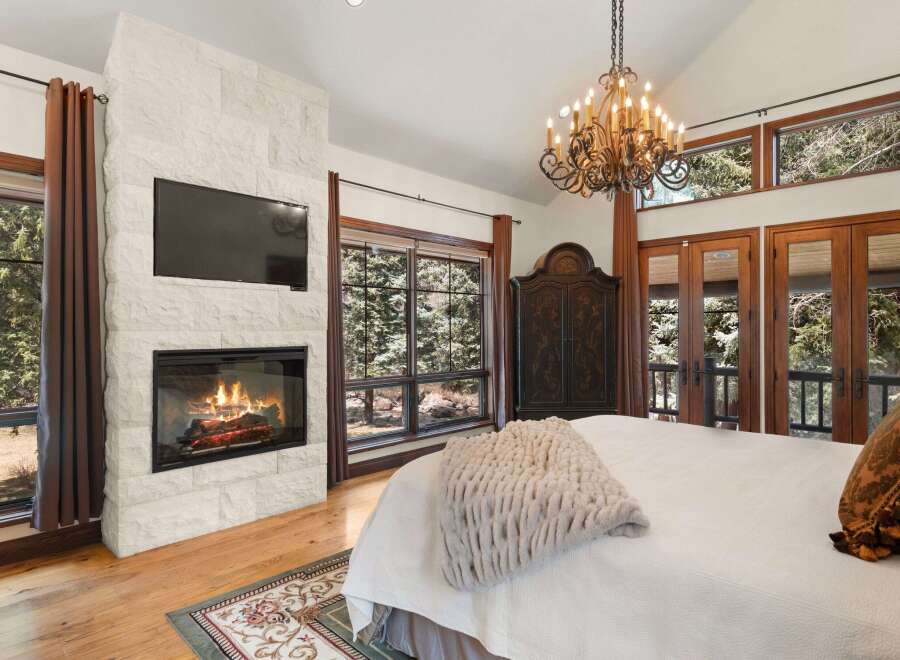 Experience luxury and comfort in this stunning bedroom featuring a cozy fireplace and a large flat-screen TV.