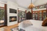 Experience luxury and comfort in this stunning bedroom featuring a cozy fireplace and a large flat-screen TV.
