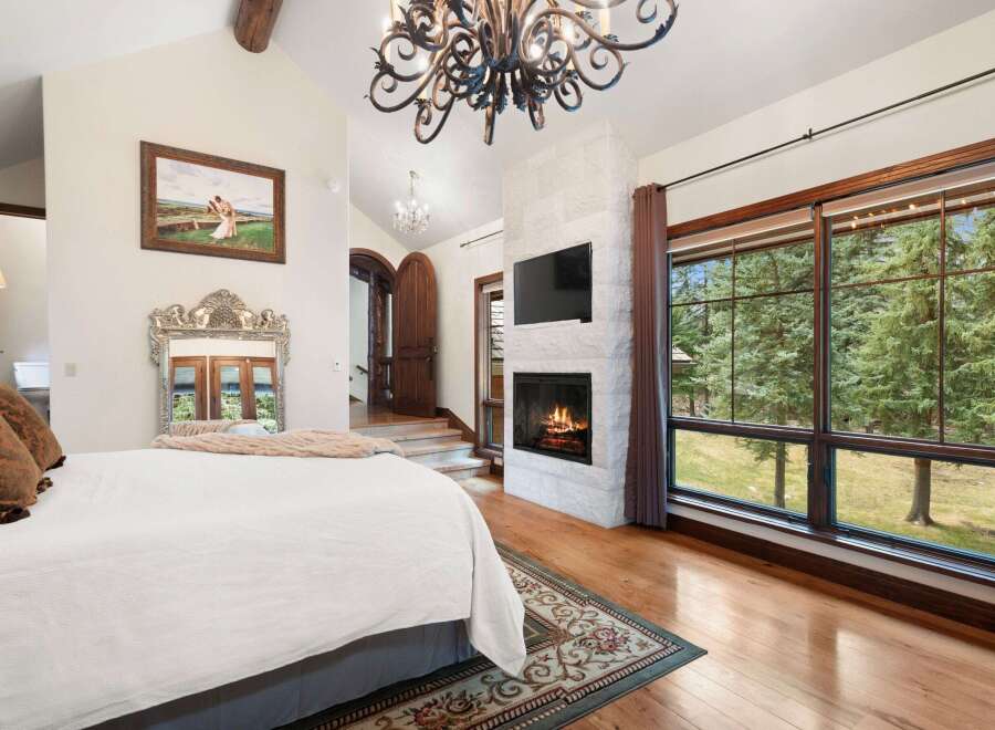 Experience luxury in this stunning bedroom featuring a cozy fireplace and a large window offering breathtaking views.