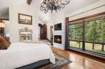 Experience luxury in this stunning bedroom featuring a cozy fireplace and a large window offering breathtaking views.