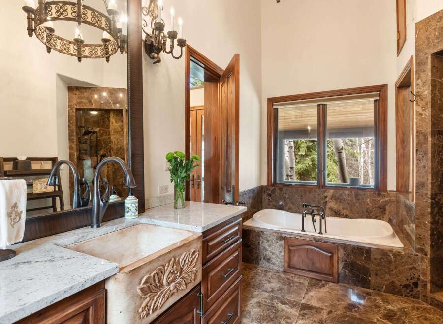 Indulge in luxury within this exquisite bathroom, showcasing a stunning combination of rich wood cabinetry and elegant marble accents.