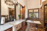 Indulge in luxury within this exquisite bathroom, showcasing a stunning combination of rich wood cabinetry and elegant marble accents.