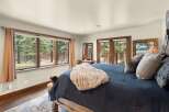 This stunning bedroom boasts a serene ambiance with its large windows offering picturesque views of the surrounding nature.