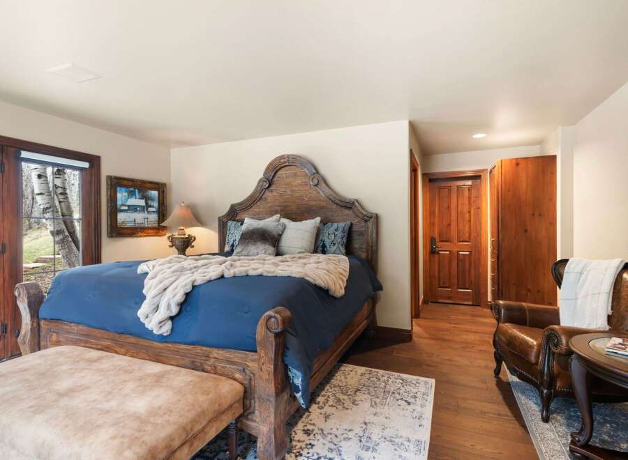 Step into luxury with this stunning bedroom, featuring a grand wooden bed frame and plush bedding.