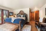 Step into luxury with this stunning bedroom, featuring a grand wooden bed frame and plush bedding.