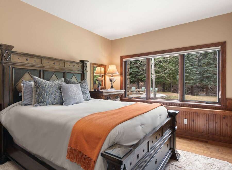 This luxurious bedroom boasts a stunning view of the surrounding landscape through its large windows.