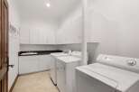 This stunning laundry room boasts ample storage with its sleek white cabinetry, perfect for keeping your space organized.