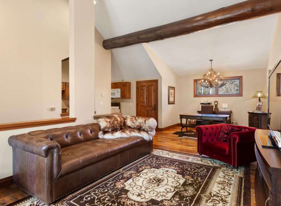 Step into luxury with this stunning property, featuring a spacious living area with a plush leather sofa and a cozy red armchair.