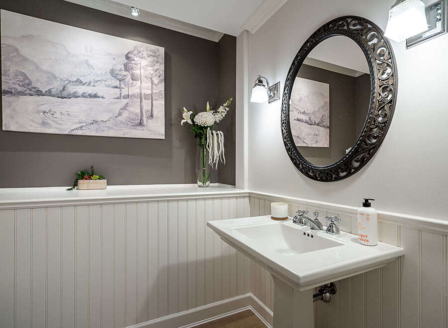 This elegant powder room features a stylish pedestal sink and a decorative oval mirror.