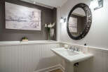 This elegant powder room features a stylish pedestal sink and a decorative oval mirror.