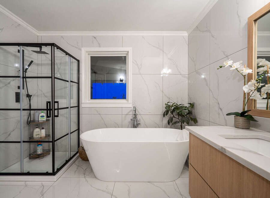 Step into luxury with this stunning bathroom! Featuring a sleek, modern design, this space boasts a beautiful freestanding tub, a glass-enclosed shower, and elegant marble-look tile.
