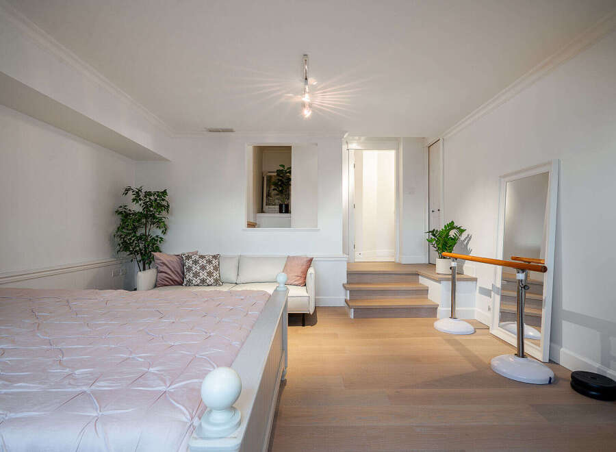 This bright and airy bedroom boasts a unique layout with a cozy seating area and a dedicated ballet barre space.