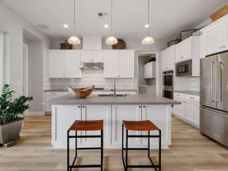 This stunning kitchen boasts a modern design with sleek white cabinetry and a spacious island, perfect for both cooking and entertaining.