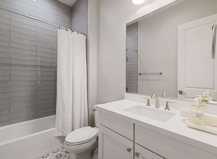 Step into this modern bathroom, featuring sleek gray tile and a pristine white vanity.