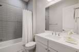Step into this modern bathroom, featuring sleek gray tile and a pristine white vanity.