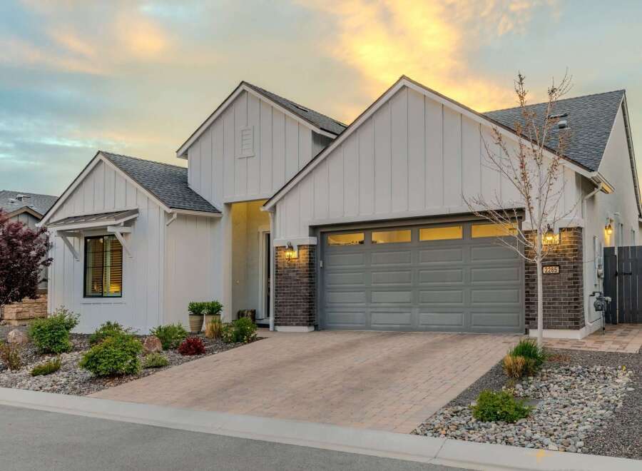 This stunning property boasts a modern farmhouse design with a charming brick facade and a welcoming front yard.