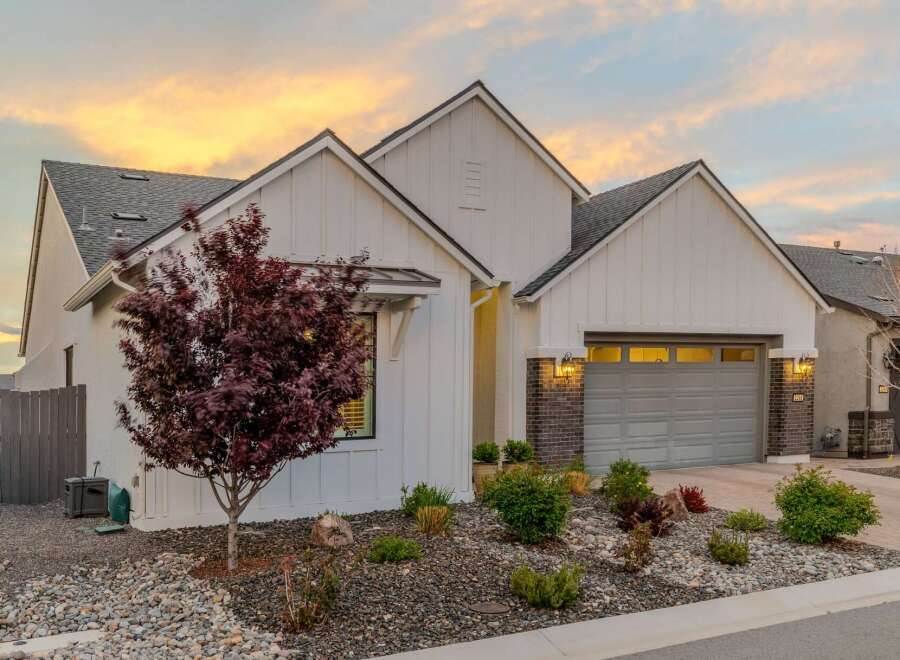This stunning property boasts a modern farmhouse design with a crisp white exterior and a charming red-leafed tree in the front yard.