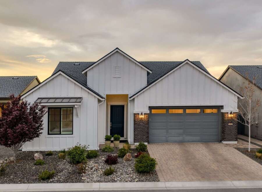 This stunning modern farmhouse boasts a beautiful exterior with a white facade and a stylish gray garage door.