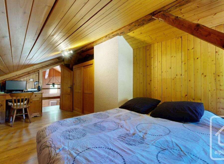 Discover the charm of this cozy bedroom featuring a unique wooden ceiling and walls, creating a warm and inviting atmosphere.