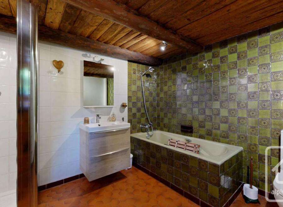 Discover the charm of this unique bathroom, featuring a rustic wooden ceiling and eye-catching green tile accents.