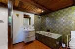 Discover the charm of this unique bathroom, featuring a rustic wooden ceiling and eye-catching green tile accents.