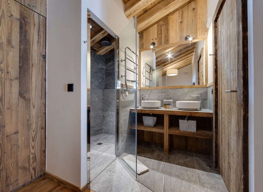 Step into luxury with this stunning bathroom featuring a modern glass shower and rustic wooden accents.