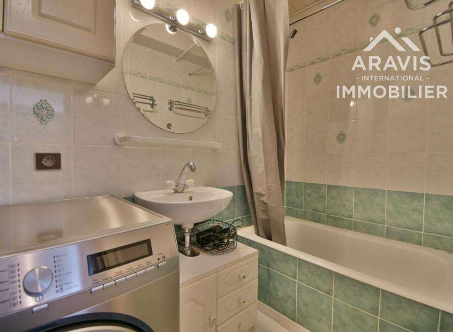 Discover this charming bathroom featuring a convenient washing machine, a stylish sink, and a relaxing bathtub.