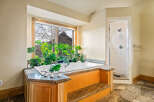 This luxurious bathroom features a stunning soaking tub nestled beneath a large window, offering a serene and private oasis.
