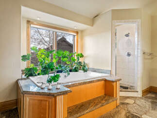 This luxurious bathroom features a stunning soaking tub nestled beneath a large window, offering a serene and private oasis.