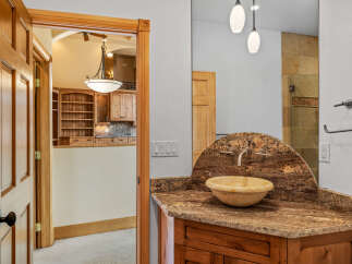 Step into luxury with this stunning bathroom featuring a unique stone countertop and a stylish vessel sink.