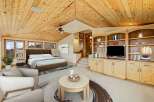 Experience luxury living in this stunning bedroom featuring a vaulted wood ceiling and a cozy seating area.
