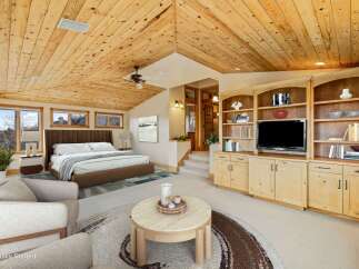 Experience luxury living in this stunning bedroom featuring a vaulted wood ceiling and a cozy seating area.